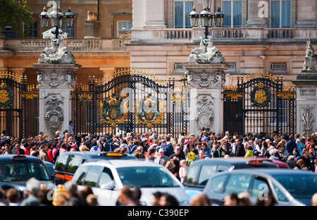 Des foules de touristes s'assembler à l'extérieur des portes de Buckingham Palace au centre de Londres avec circulation Banque D'Images