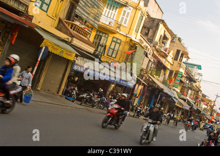 Grand angle horizontal de 'bâtiments' tubulaire le long d'une rue dans le vieux quartier de Hanoi avec les mobylettes, motos et scooters. Banque D'Images