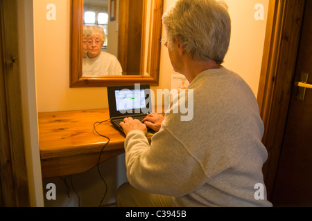 UK femme âgée dans la chambre d'hôtel à essayer de se connecter à l'ordinateur portable en utilisant la connexion WiFi internet Banque D'Images