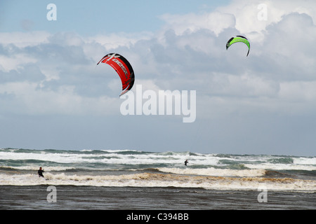 Un couple kite surfeurs profitant des vagues de Seaside, Oregon sur un jour nuageux Avril. Banque D'Images