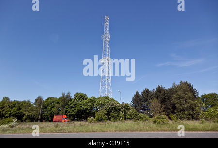 Un mât d'antenne de communications blanches contre un ciel bleu ensoleillé. Banque D'Images