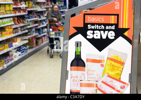 Un Sainsbury's basics étagère, avec un nouveau client de navigation dans l'arrière-plan, au nord de Londres. Banque D'Images