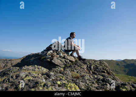 Walker assis sur le cairn du sommet du veau Crag, Lake District, Cumbria Banque D'Images