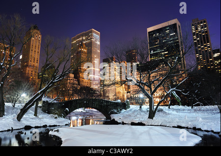 New York Ville Manhattan panorama Central Park en hiver avec la neige, le gel ; pont lake et gratte-ciel au crépuscule. Banque D'Images