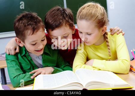 Portrait de deux gars et une fille reading book in classroom Banque D'Images