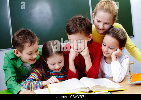 Portrait de groupe sympathique reading book in classroom Banque D'Images