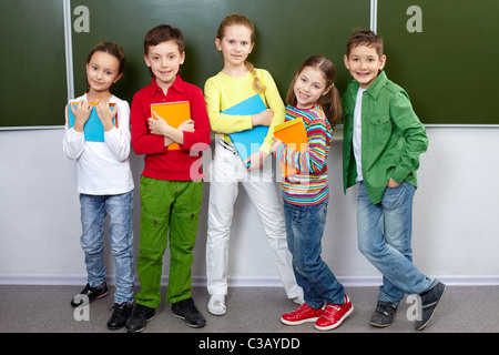 Portrait de cinq élèves looking at camera in classroom Banque D'Images