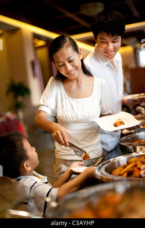 Mère d'aider son fils à l'occasion d'un buffet Banque D'Images