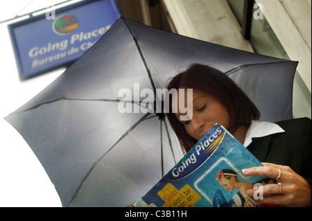 Une dame n'envisage de s'éloigner de la pluie à l'extérieur d'un Going Places store à Londres ; partie du groupe Thomas Cook. Banque D'Images