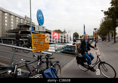 Les cycles d'une fille d'un pont sur un canal à Amsterdam Banque D'Images