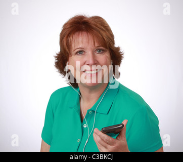 Smiling middle-aged woman est à l'écoute de la musique sur son smartphone, white background, studio shot, le 20 avril 2011 © KAndriotis Banque D'Images