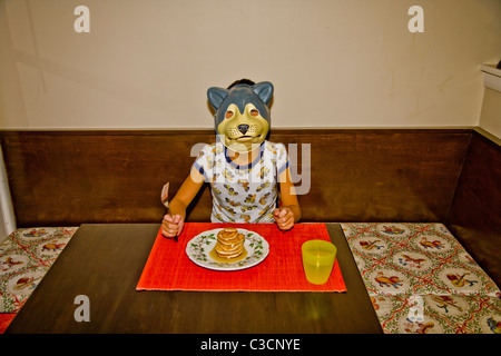 Garçon portant un masque de chien à table Banque D'Images