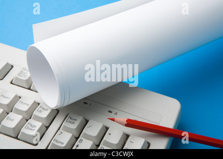 Close-up of red crayon, papier plié et une partie de clavier sur la surface bleue Banque D'Images