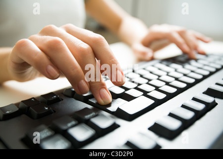 Close-up of female hands en appuyant sur la touche entrée sur le clavier noir Banque D'Images