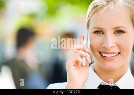 Portrait de jolie femme qui parle d'affaires par téléphone mobile et à la recherche à l'appareil photo avec sourire Banque D'Images