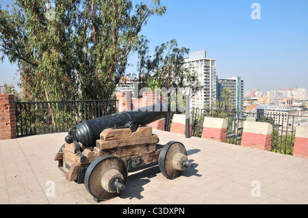 Ciel bleu de midi Gun cannon, sommet Cerro Santa Lucia, à la recherche sur les édifices patrimoniaux et gratte-ciel de Centro, Santiago, Chili Banque D'Images