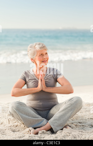 Senior woman practicing yoga on the beach Banque D'Images