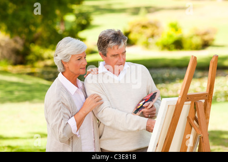 Couple de retraités peinture dans le parc Banque D'Images