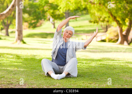 Senior woman doing her s'étend dans le parc Banque D'Images