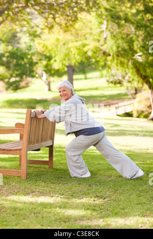 Senior woman doing her s'étend dans le parc Banque D'Images