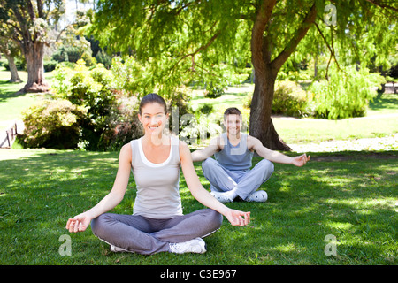Couple practicing yoga in the park Banque D'Images