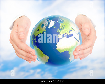 La terre dans la main de l'homme contre le ciel bleu. Concept de protection de l'environnement. Banque D'Images