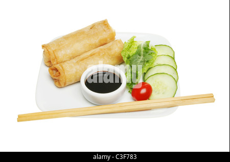 Rouleaux de crêpes chinoises sur une assiette avec la sauce de soja ; et une trempette salade ; baguettes sur le bord de la plaque Banque D'Images