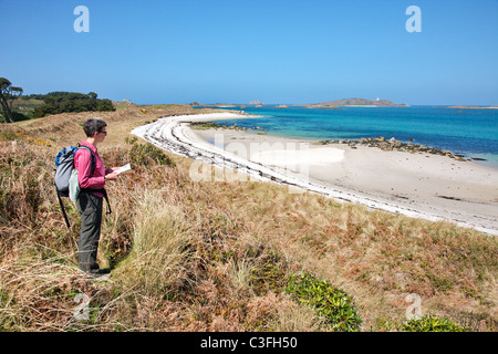 Femme avec walker la carte la recherche sur plage de quartz blanc à Pentle Bay sur Tresco dans les îles Scilly Banque D'Images