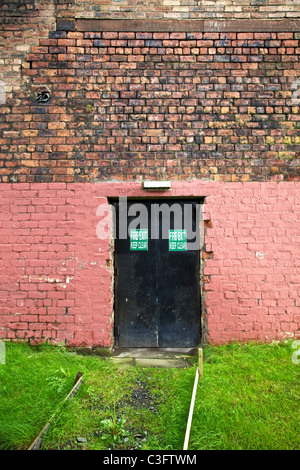 Feu noir porte de sortie à un mur de brique rose à Glasgow, Écosse, Royaume-Uni Banque D'Images