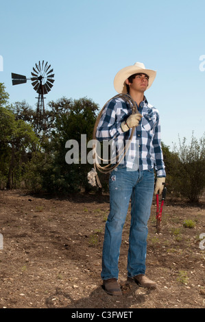 Jeune cowboy sur une ferme avec moulin ranch dans l'arrière-plan Banque D'Images