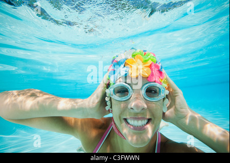 Hispanic woman in retro bonnet de bain sous l'eau à la piscine Banque D'Images