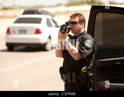 Agent de police de sexe masculin utilise des armes à feu de vitesse radar pour attraper les conducteurs excès de vitesse sur l'autoroute à Austin, Texas USA Banque D'Images