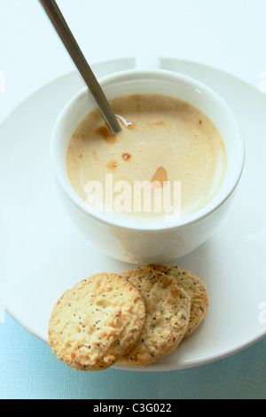 Le café dans une tasse et soucoupe blanc et les biscuits sur un fond bleu Banque D'Images