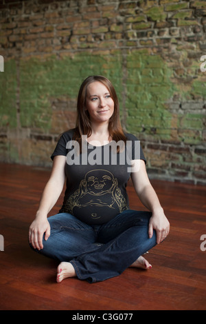 Smiling pregnant Caucasian woman sitting on floor Banque D'Images