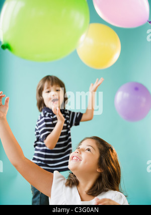 Frères et sœurs hispaniques jouant avec des ballons Banque D'Images