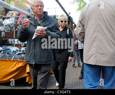 Amsterdam, Pays-Bas. Man eating chips / frites en marché aux puces de Waterlooplein Banque D'Images
