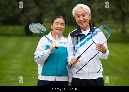 Senior Couple Holding raquettes de badminton dans un parc Banque D'Images