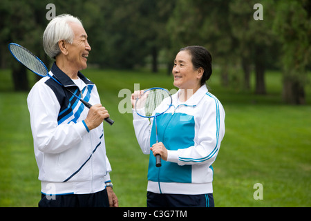 Senior Couple Holding raquettes de badminton dans un parc Banque D'Images
