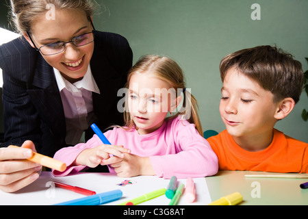 Image of teacher holding surligneur et à la photo de la fille au garçon mignon tout en exprimant son opinion Banque D'Images