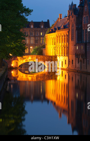 Pont illuminé et ses bâtiments reflétant dans l'eau au crépuscule, le centre historique de Bruges, Belgique Banque D'Images