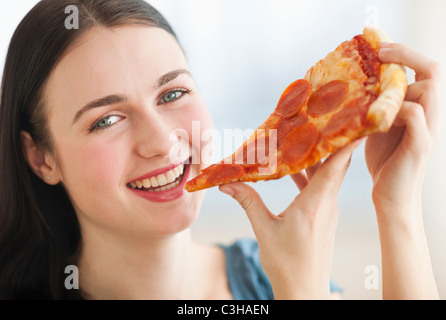 Portrait of smiling young woman eating pizza Banque D'Images