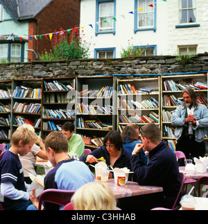 Les adolescents les adolescents les garçons mangent des nouilles à côté de livres sur les étagères dans un café extérieur à l'Honesty Bookshop dans le parc du château pendant le Hay Book Festival Hay on Wye, pays de Galles, Royaume-Uni KATHY DEWITT Banque D'Images