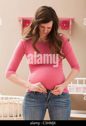 Jeune femme enceinte à boutonner jeans Banque D'Images