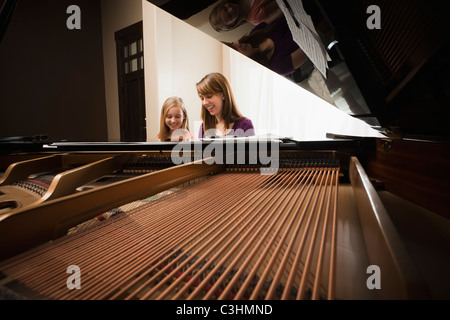 Girl (8-9) et la mère jouant grand piano Banque D'Images