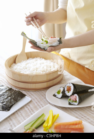 Closeup of hands faire part-sushi roulé Banque D'Images