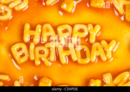 Pâtes en forme Alphabet formant Joyeux anniversaire à la sauce tomate Banque D'Images