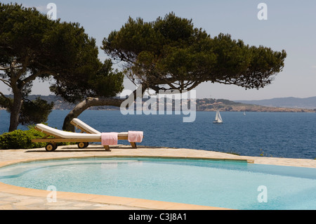Deux chaises longues sur le côté d'une piscine extérieure avec vue sur la Méditerranée Banque D'Images