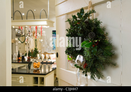 Couronne de Noël sur fond blanc porte ouverte avec vue jusqu'à la cuisine avec des décorations de fête Banque D'Images