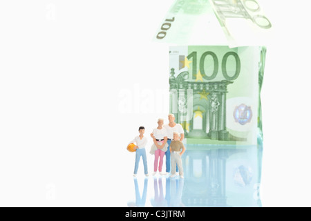 Figurines standing in front of house de 100 euro notes Banque D'Images