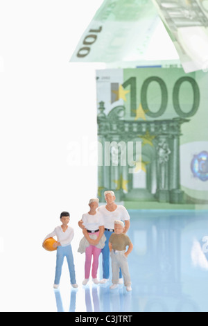 Figurines standing in front of house de 100 euro notes Banque D'Images